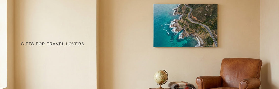 Gifts for travel lovers: a cozy reading corner with a leather armchair, a vintage suitcase and a turquoise coastline canvas on the wall