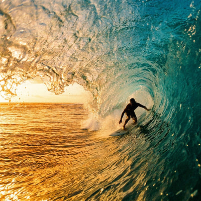 Surfing wall decor, a surfer inside a blue barrel wave with sunlit spray along the curling lip