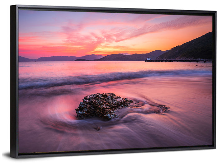 Pink Sunset Over Rock and Pier Wall Art as a framed canvas
