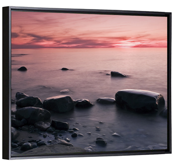 Pink Dusk Lakeshore with Silhouetted Rocks Wall Art as a framed canvas
